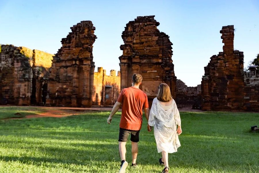 Pareja caminando hacia las ruinas jesuíticas de San Ignacio